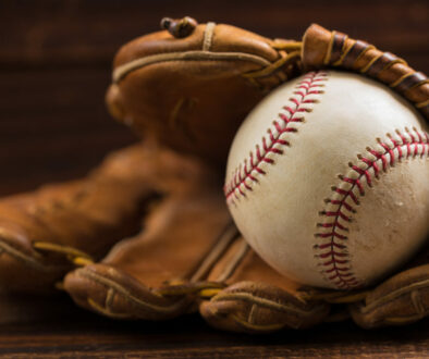 Leather baseball glove and ball on a wooden bench